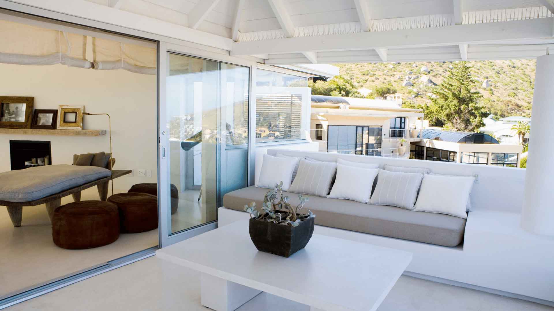 Covered verandah with built-in lounge seating overlooking hillside homes