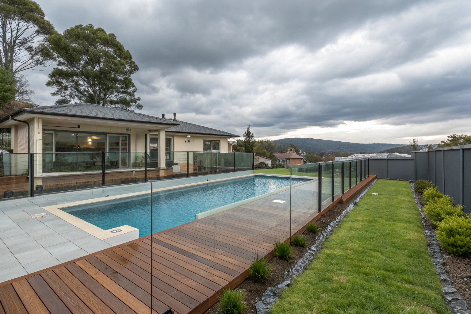 Pool deck with glass safety fence barriers around a Hobart backyard pool